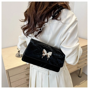 Close-up of black pleated leather bag featuring a large silver butterfly metal buckle detail