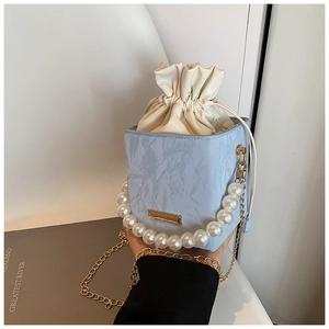 Detail of blue marble bucket bag with pearl handle, gold chain and drawstring closure