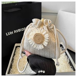 Close-up of handmade woven straw bucket bag featuring a large white daisy flower detail
