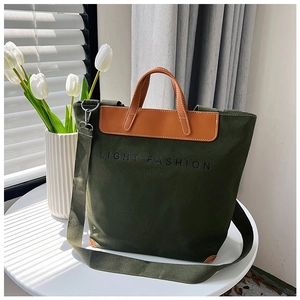 Detalle de bolso tote de lona verde oscuro con asas de cuero marrón y estampado fashion