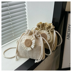 Detailed close-up of straw bucket bags with daisy flower appliques and drawstring closure