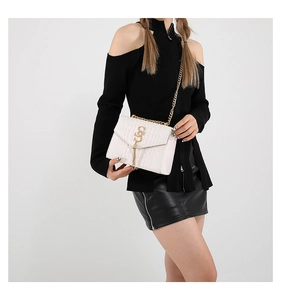 Détail du sac blanc à motif crocodile avec logo doré et bandoulière en chaîne