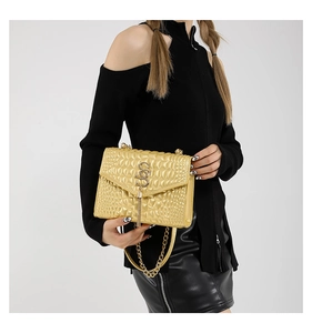 Détail du sac bandoulière doré métallisé avec texture matelassée porté par le mannequin