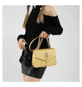 Détail du sac doré en similicuir avec motif crocodile et pendentif logo S métallique