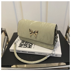 Detail of light green textured leather bag with a vintage gold butterfly metal clasp