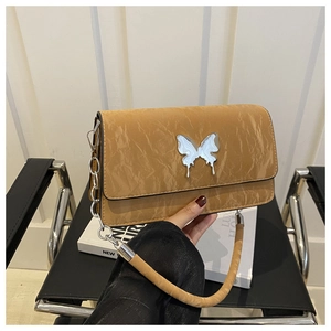 Detail of khaki shoulder bag with pleated leather texture and silver butterfly ornament