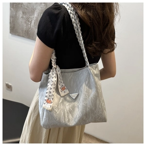 Detail view of silver metallic tote bag with woven shoulder strap and ribbon decor