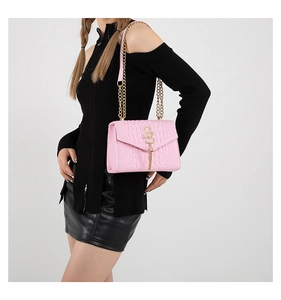 Gros plan sur la texture crocodile rose et la chaîne dorée de ce sac à bandoulière