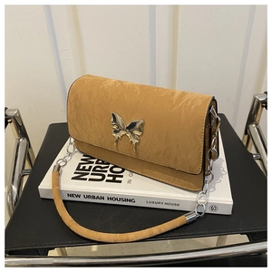 Detailed shot of khaki pleated bag featuring a silver metal butterfly buckle and chain strap
