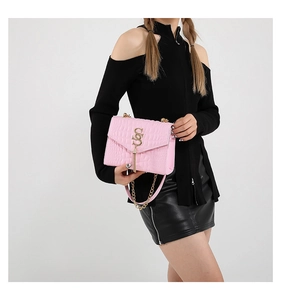 Détail du sac à bandoulière rose embossé crocodile avec logo doré et pompon chic