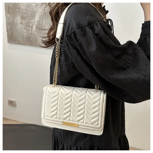 Close-up of white quilted chain bag with V-stitch pattern and gold metal buckle detail