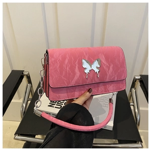 Detail of pink crossbody bag with pleated leather texture and a silver butterfly buckle