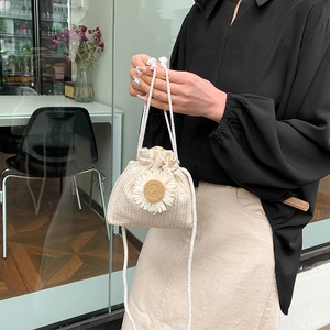 Straw drawstring bucket bag with large floral accent and shoulder strap for summer vacation