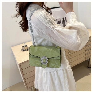 Detail of green patent leather crossbody bag with water ripples and silver buckle