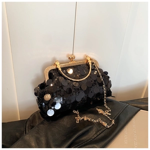 Detail of black sequin evening bag featuring gold metal frame and spherical clasp