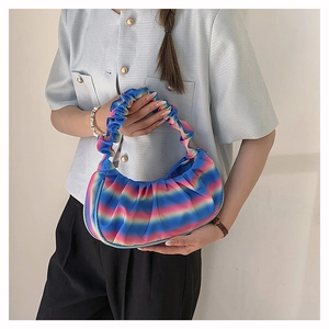Detailed shot of a pleated rainbow cloud bag with vibrant color gradient held by model