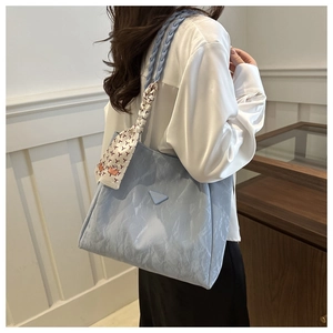 Detail of light blue wrinkled tote bag with braided rope strap and decorative silk scarf
