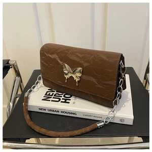 Detail of dark brown crinkled leather shoulder bag with a metallic butterfly clasp