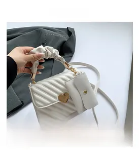 Detail of white quilted crossbody bag with golden heart clasp and ruched top handle