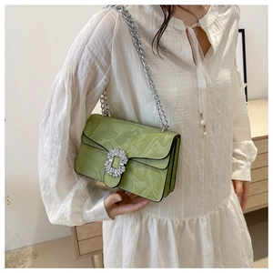 Detail of light green chain bag with rhinestone buckle and accordion pleat structure