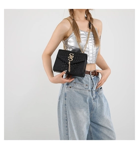 Détail d'un sac à bandoulière en similicuir croco avec pompon doré et logo SS