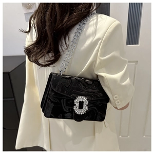 Detail of glossy black marble texture shoulder bag with chunky silver chain and crystal buckle