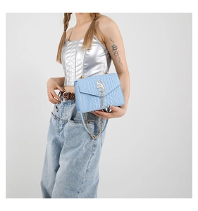 Détail du sac à main bleu clair en simili crocodile avec boucle dorée et pompon métal