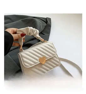Close-up of cream white quilted PU leather handbag with gold heart lock and ruched handle