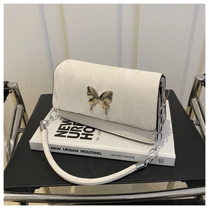 Close-up of beige wrinkled shoulder bag with a silver liquid metal butterfly buckle