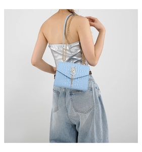 Gros plan du sac bleu clair à motif crocodile avec boucle dorée en S et chaîne élégante