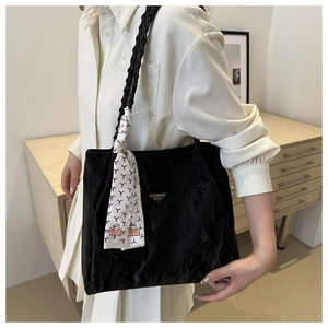 Detail of black pleated tote bag with woven shoulder strap and decorative floral scarf