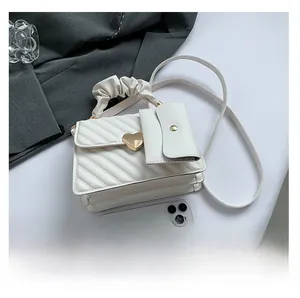 Detailed view of white quilted crossbody bag with heart buckle and cloud handle