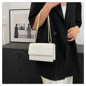 Close-up of white V-quilted faux leather shoulder bag with gold metal chain strap detail