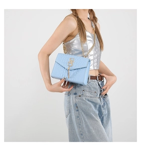Détail du sac bleu clair à motif crocodile avec logo S doré et gland à franges