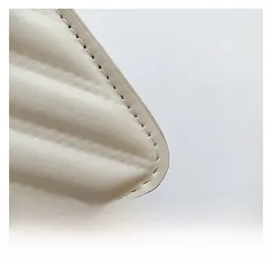 Macro shot of V-quilted faux leather detailing and precise stitching on ivory crossbody bag