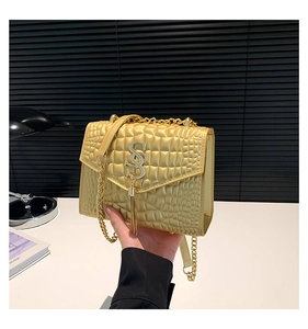 Détail du sac bandoulière doré à motif crocodile avec logo SS en métal et pompon chic