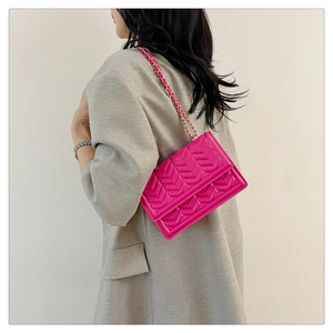 Close-up of magenta quilted chain crossbody bag styled with a grey blazer outfit