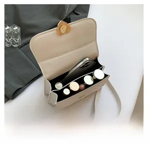 Detail of cream flap bag interior showing compartments with phone and lipsticks inside