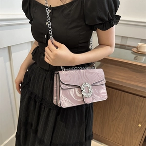 Pink marble chain shoulder bag with oversized rhinestone buckle on black dress