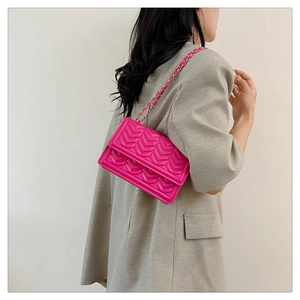 Detail of vibrant hot pink chevron quilted crossbody bag with gold chain strap