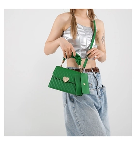 Detail of green leather bag featuring diagonal texture and golden heart clasp with mini pouch