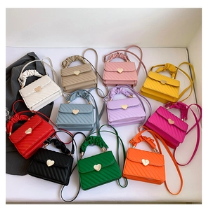 Flat lay of small crossbody bags with heart-shaped gold buckles and cloud handles