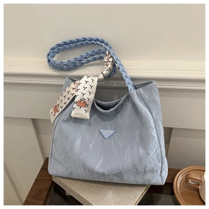 Detail of light blue pleated tote bag with woven strap and silk scarf on vintage books