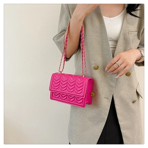 Detail of pink quilted crossbody bag with golden chain strap on a model outfit