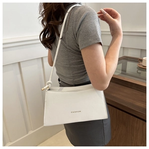 Détail du sac sous l'aisselle en cuir blanc avec texte Fashion et nœud sur la bandoulière