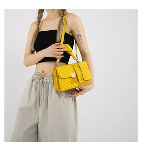 Detail of yellow quilted crossbody bag with golden heart buckle and small coin purse