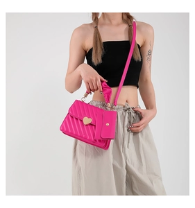 Detail of rose pink quilted crossbody bag with heart buckle and pleated handle