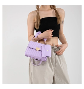 Detail of lavender quilted handbag featuring a golden heart clasp and ruffled handle grip