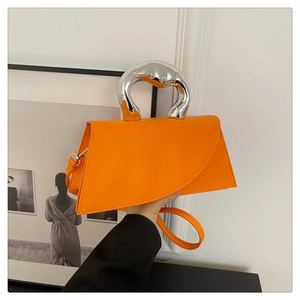 Detail of orange geometric crossbody bag with a modern silver asymmetrical metal handle
