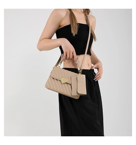 Detail of khaki textured crossbody bag with gold heart lock and mini hanging purse